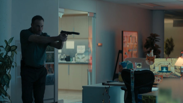 A gunman walks through an office past a desk decorated for a birthday in Reacher