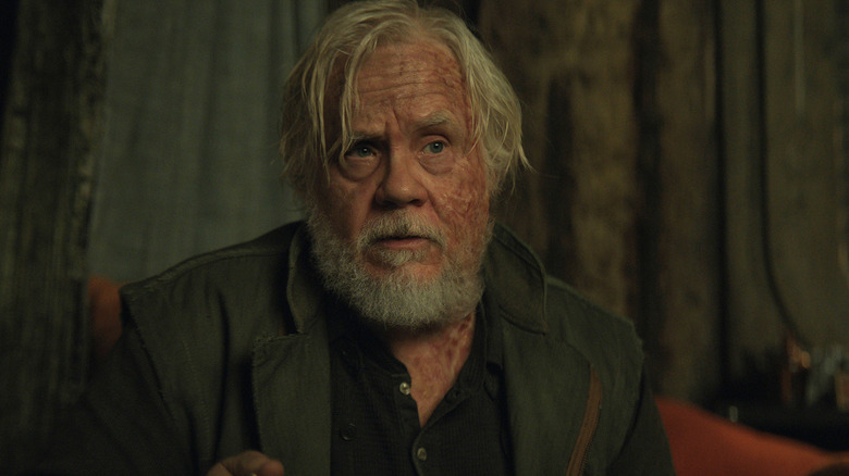 Tim Robbins' Bernard Holland sits in a chair in Silo
