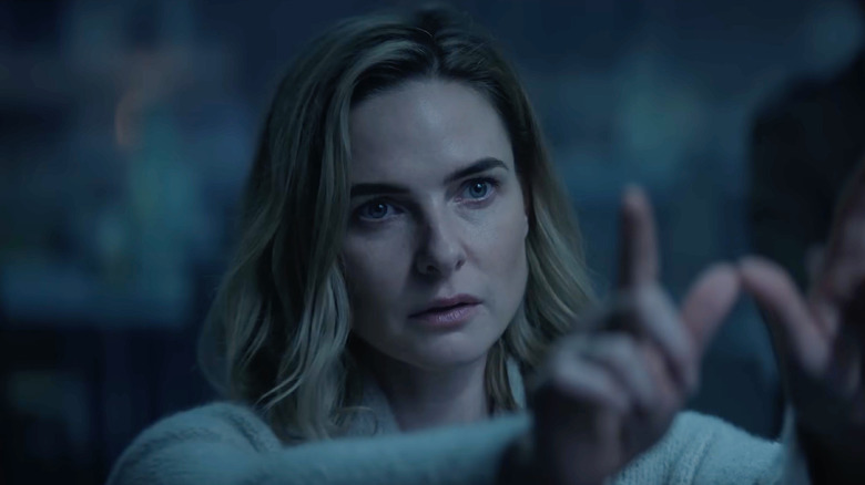 Rebecca Ferguson as Juliette Nichols staring into the distance and holding up her fingers in a W shape in Silo