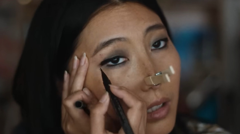 Shirley Chen as Joan Huang with a clothes pin on her nose, putting on eyeliner, in Slanted