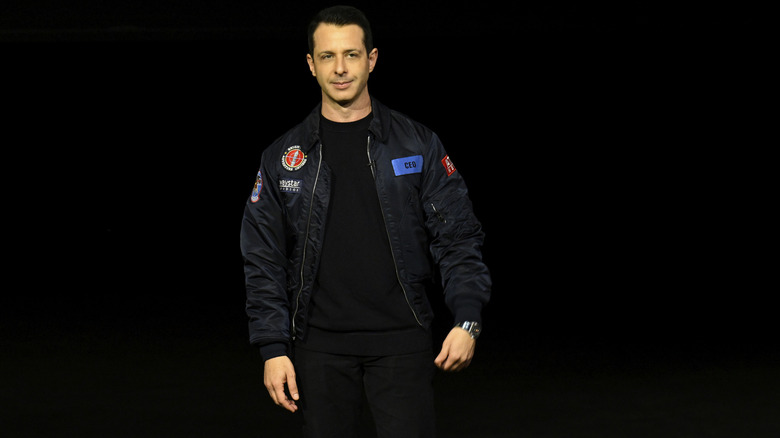 Kendall in a flight suit jacket on stage at Succession