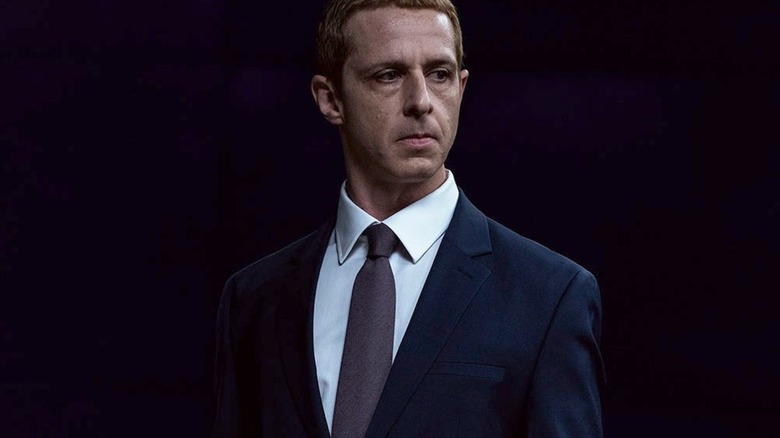 Jeremy Strong as Mark Zuckerberg wearing a suit and tie in front of a black backdrop in The Social Reckoning