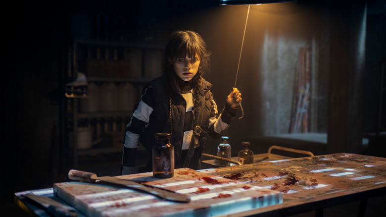 Wednesday standing over bloody table