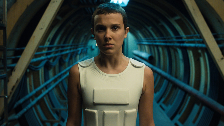 Mille Bobby Brown as Eleven standing in a tunnel in a white vest in Stranger Things