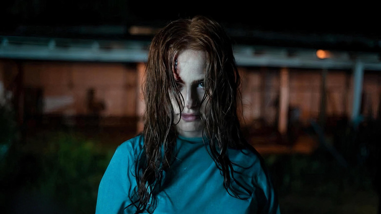 Madelaine Petsch as Maya with a cut on her forehead standing in a hospital gown outside in The Strangers: Chapter 2