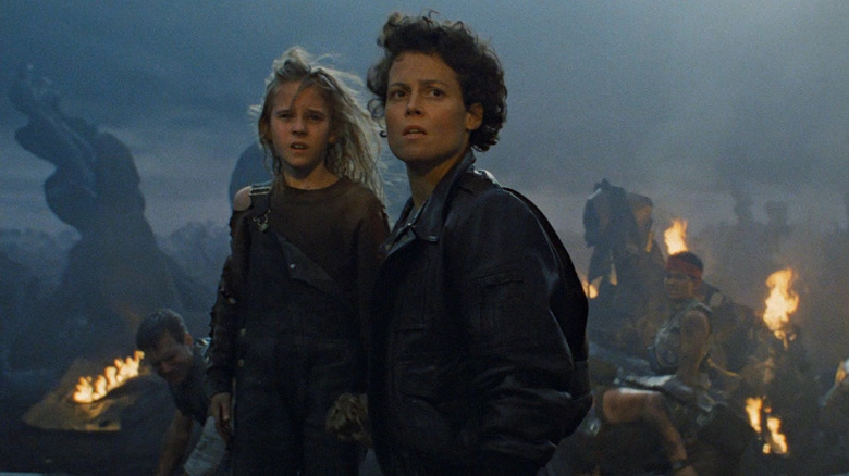 Ripley (Sigourney Weaver) carries the young orphaned Newt (Rebecca Jorden) in Aliens (1986)