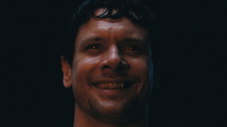 Jack O'Connell's Remmick smiling with his eyes glowing red in Sinners