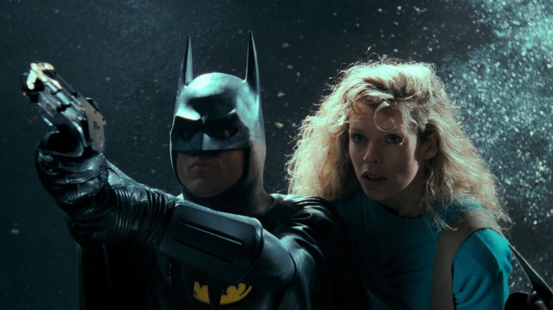 Batman shoots his grappling hook while Vicki Vale watches in Batman