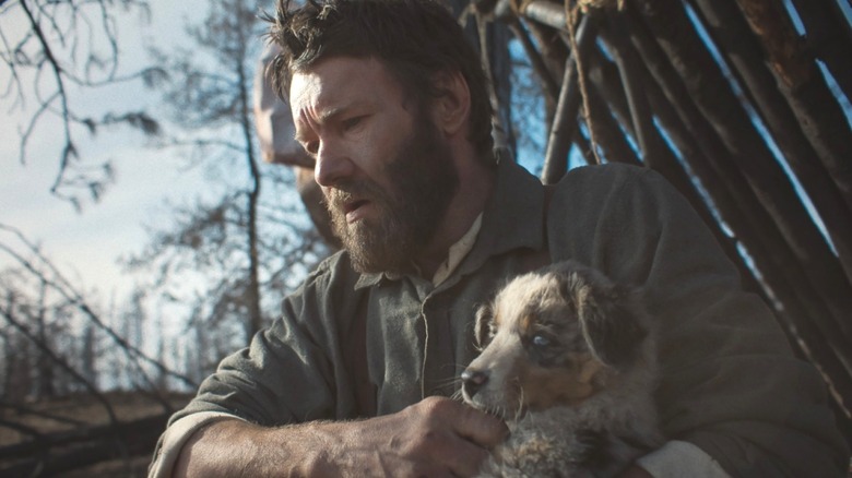 Robert Grainier looking hopeless while holding a puppy in Train Dreams