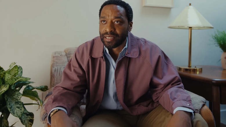 Chiwetel Ejiofor as Clark sitting in a chair at a therapy appointment with an agitated expression on his face in Backrooms