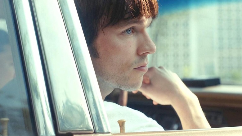 Nicholas Hoult as Bob Mathews sitting in a car in The Order