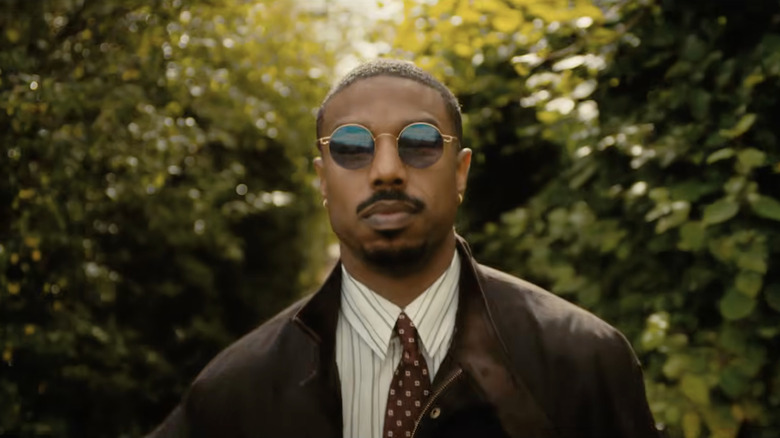 Michael B. Jordan as Thomas Crown wearing sunglasses and a suit in The Thomas Crown Affair (2027)