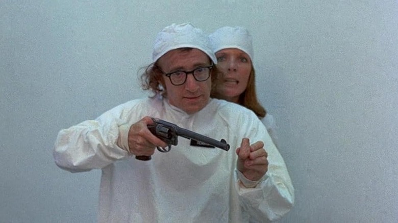 Luna hiding behind Miles brandishing a gun in white outfits in Sleeper