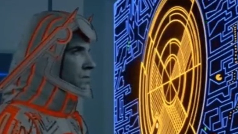 Character looking at screen with Pacman on in Tron