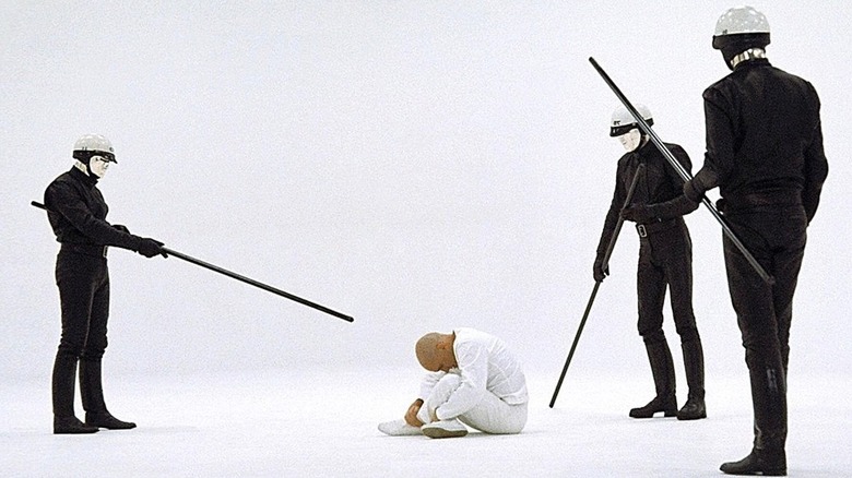 THX 1138 (1971)లో పోలీసులచే చుట్టుముట్టబడిన తెల్లటి గది అంతస్తులో THX 1138