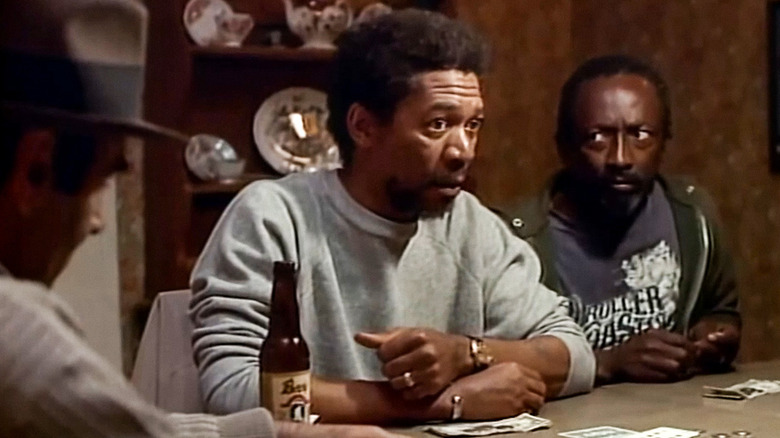 Morgan Freeman as Tony sitting at a table with cards and a beer on The Twilight Zone