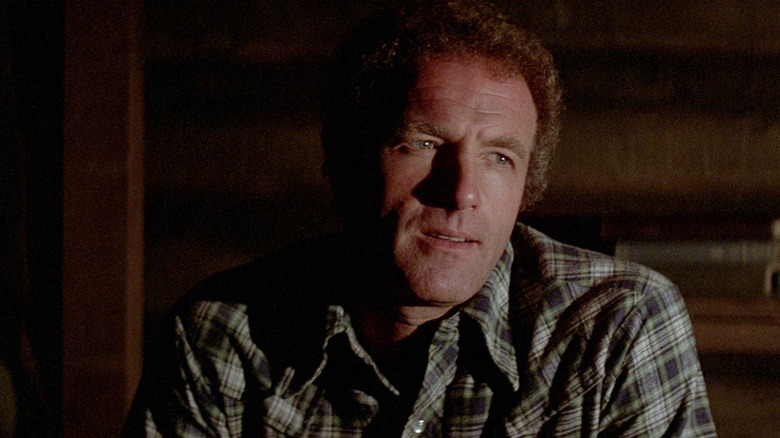 James Caan as Frank Athearn sitting in the shadows in Comes a Horseman