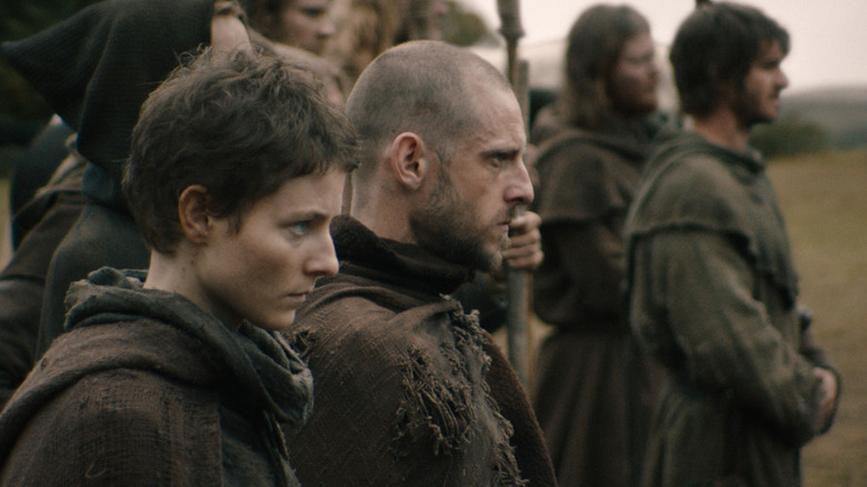 Thomasin McKenzie as Alyce standing next to Jamie Bell as John Ball alongside an army in The Uprising