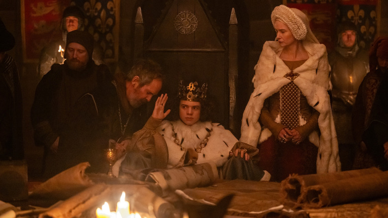 Woody Norm as King Richard III seated on a throne next to Tom Hollander as Treasurer Hales and Katherine Waterston as The Countess in The Uprising