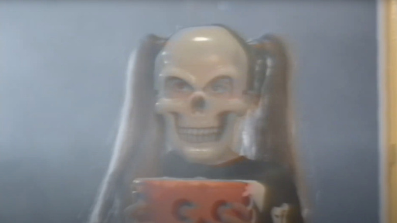 A small child dressed like a skeleton holding a plastic halloween bucket in V/H/S/Halloween