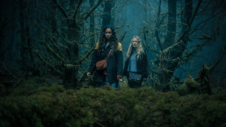 Georgina Campbell as Ciara and Dakota Fanning as Mina walking through a creepy-looking forest in The Watchers