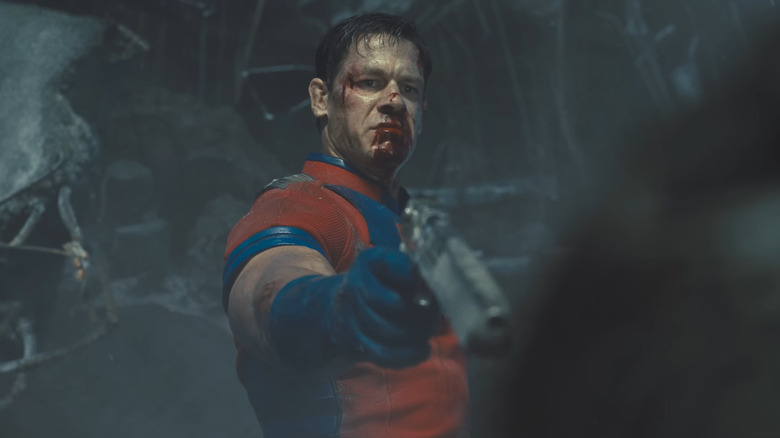 John Cena as Peacemaker aims a gun at Ratcatcher