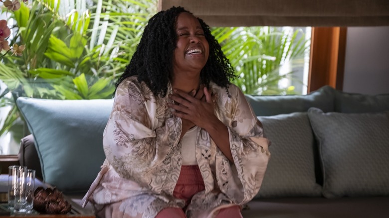 Belinda laughing with her hand on her chest in The White Lotus
