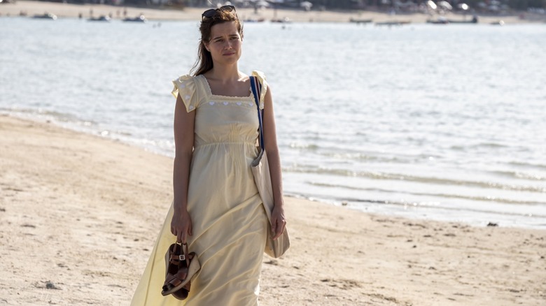 Piper holding her shoes and walking on the beach in The White Lotus