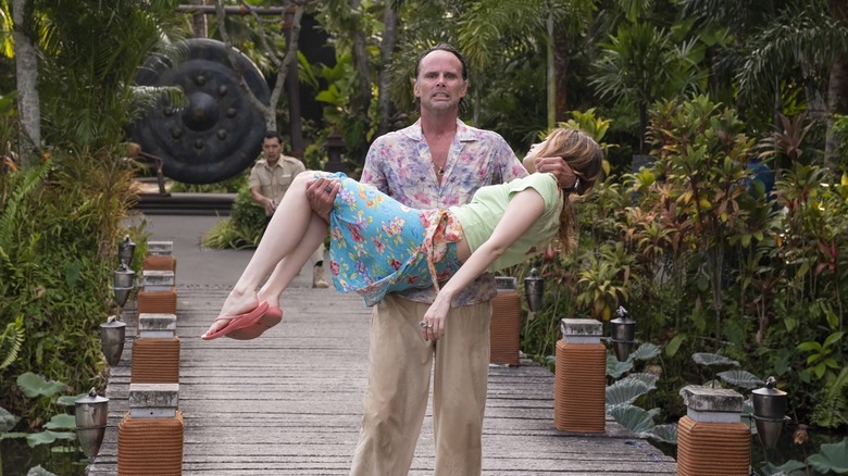 Rick carrying Chelsea with Gaitok behind him on The White Lotus