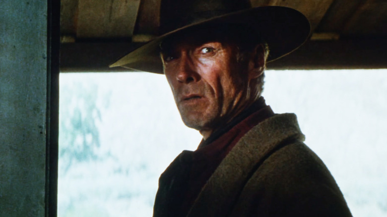 Clint Eastwood's William Munny looks across frame as he stands in a doorway in Unforgiven