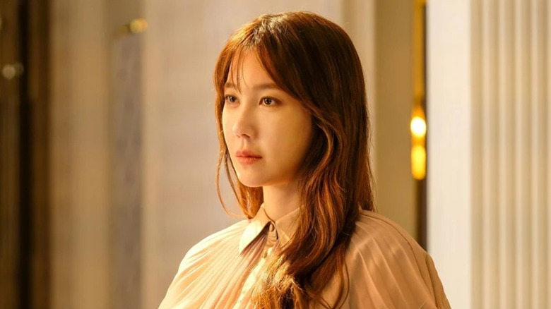 Shim Su-ryeon (Lee Ji-ah) stands in a foyer in The Penthouse: War in Life