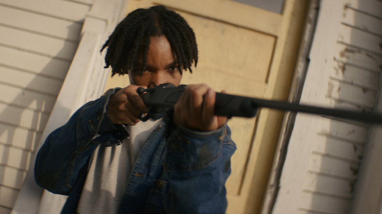 Peyton Jackson segurando uma arma na varanda na mulher no quintal