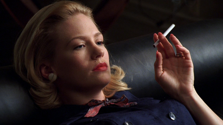 A close-up of Betty Draper looking desperate while holding a cigarette