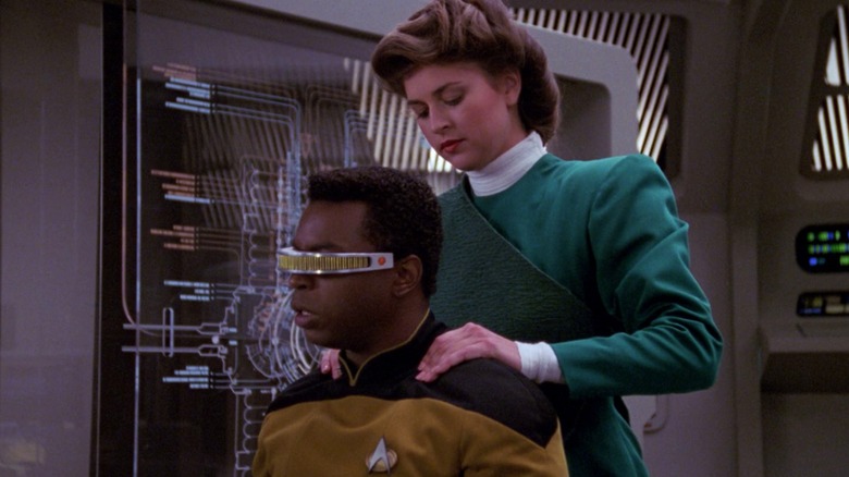 a holographic Leah Brahms (Susan Gibney) gives Geordi (LeVar Burton) a back massage