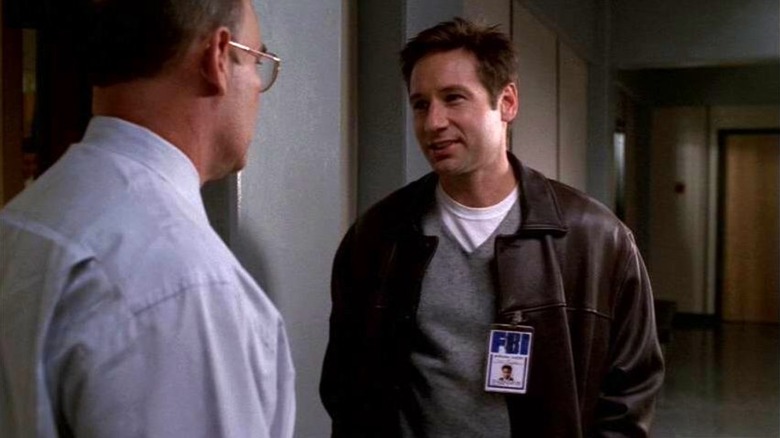 Mulder, wearing an FBI visitor badge, talking to Skinner in an episode of The X-Files.