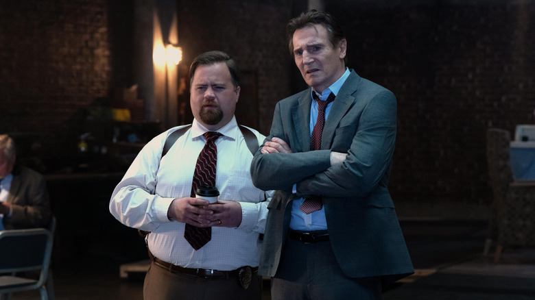 Paul Walter Hauser as Ed Hocken Jr. standing next to Liam Neeson as Frank Drebin Jr. looking confused in The Naked Gun (2025)