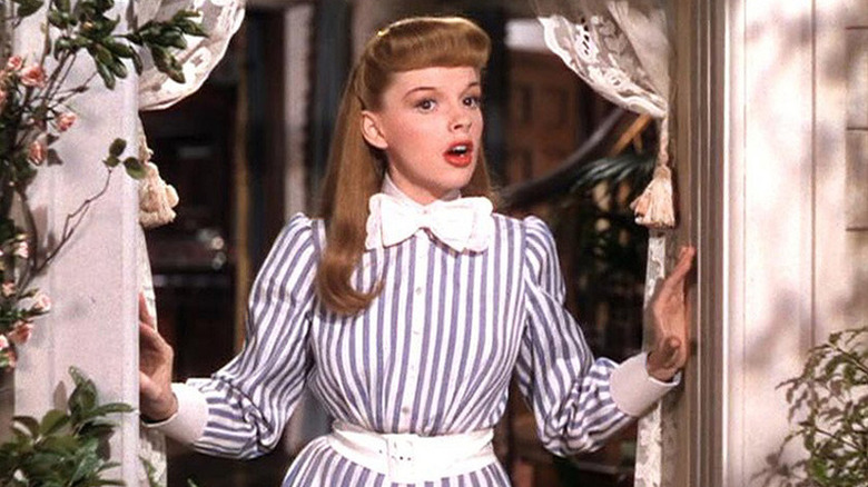 Esther singing in a window in a striped dress in Meet Me in St. Louis