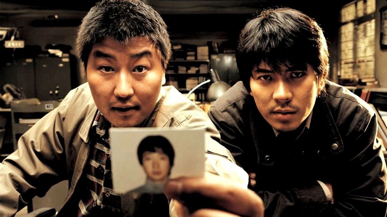 Detectives in Memories of Murder hold up a photo