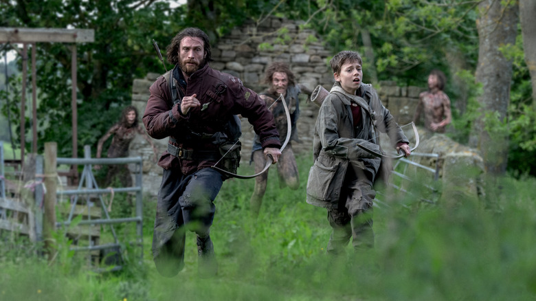 Aaron Taylor-Johnson as Jamie and Alfie Williams as his son Spike running away from infected in 28 Years Later