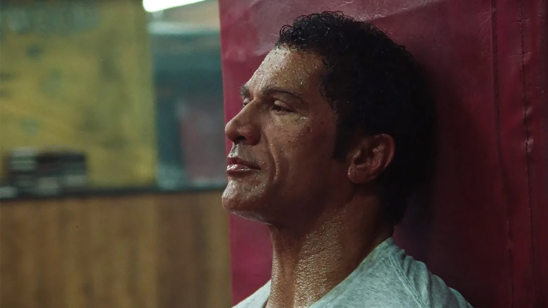 Dwayne Johnson as Mark Kerr, sweaty and sitting on the floor of a gym, in The Smashing Machine