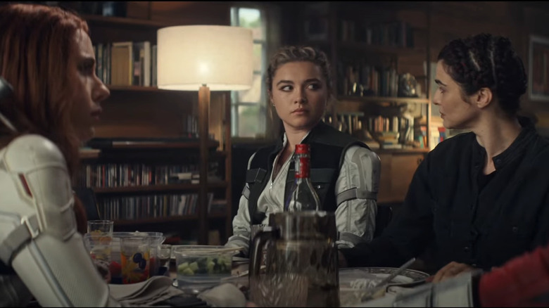 Scarlett Johansson as Natasha sitting at a table with Florence Pugh as Yelena, Rachel Weisz as Melina, and David Harbour as Alexei in Black Widow