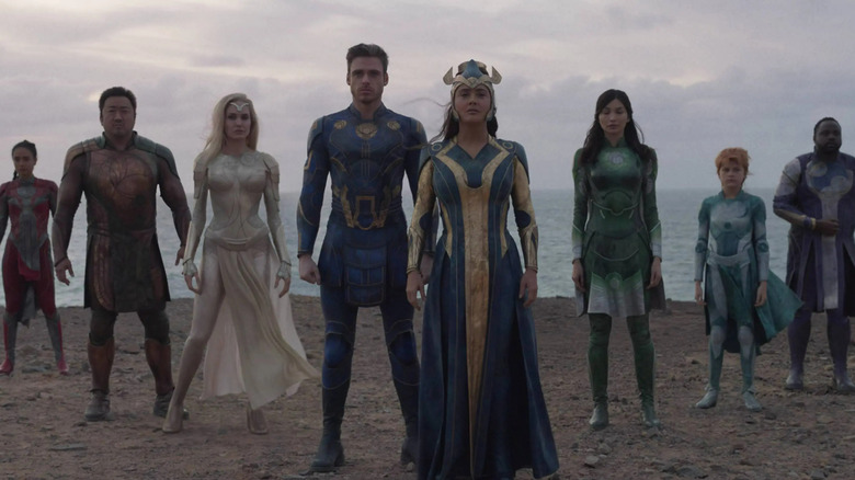 Lauren Ridloff as Makkari, Don Lee as Gilgamesh, Angelina Jolie as Thena, Richard Madden as Ikaris, Salma Hayek as Ajax, Gemma Chan as Sersi, Lia McHugh as Sprite, and Brian Tyree Henry as Phastos standing in Eternals
