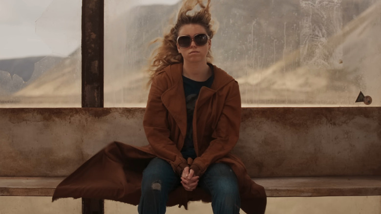Milly Alcock as Kara Zor-El sitting at the bus stop in Supergirl