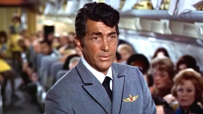 Dean Martin's Vernon Demerest on a passenger plane aisle surrounded by nervous passengers in Airport