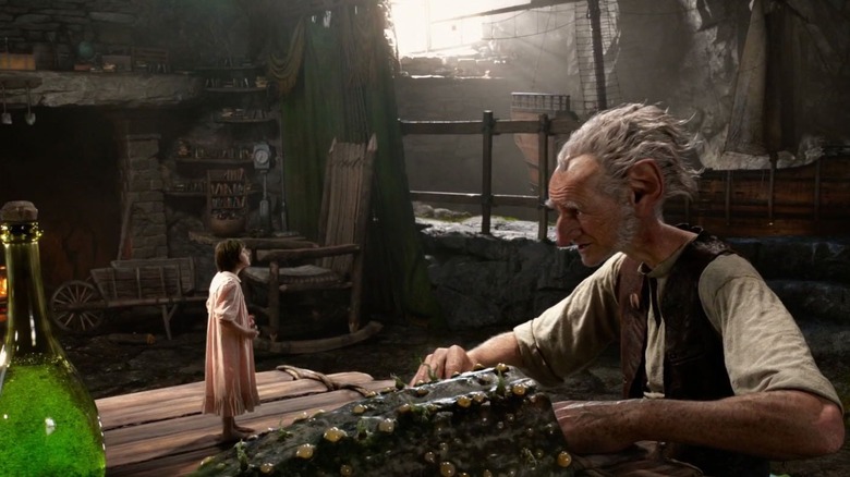 சோஃபி ஒரு மேசையில் நின்று BFG இல் BFG உடன் பேசுகிறார்