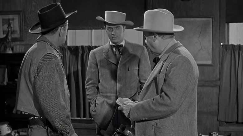 Bill Lowrey standing between two guys in hats in Blazing Across the Pecos