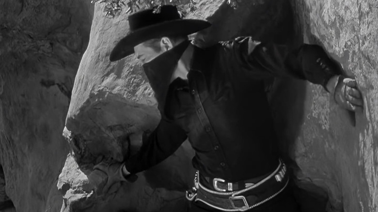 The Durango Kid perched on a cliff in Blazing Across the Pecos