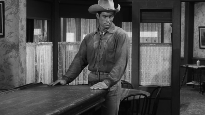 क्लिंट वॉकरचा चेयेने बॉडी बारच्या शेवटी त्याच्या डावीकडे पाहत उभा आहे