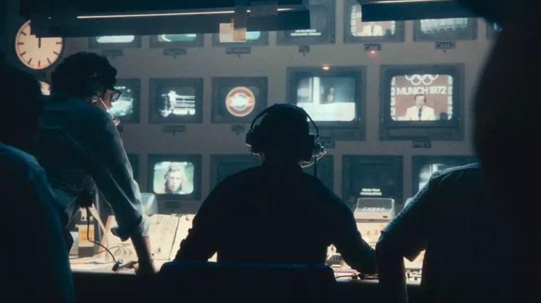 A group of TV directors in a control room, looking at a wall of TV monitors in September 5