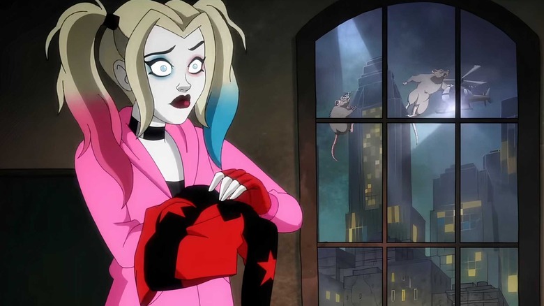 Kaley Cuoco like Harley Quinn standing near a window showing Gotham City under attack in a scene from Harley Quinn